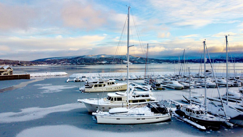 A sailing yacht berthed in a harbour in Northern Norway in winter with ice and snow